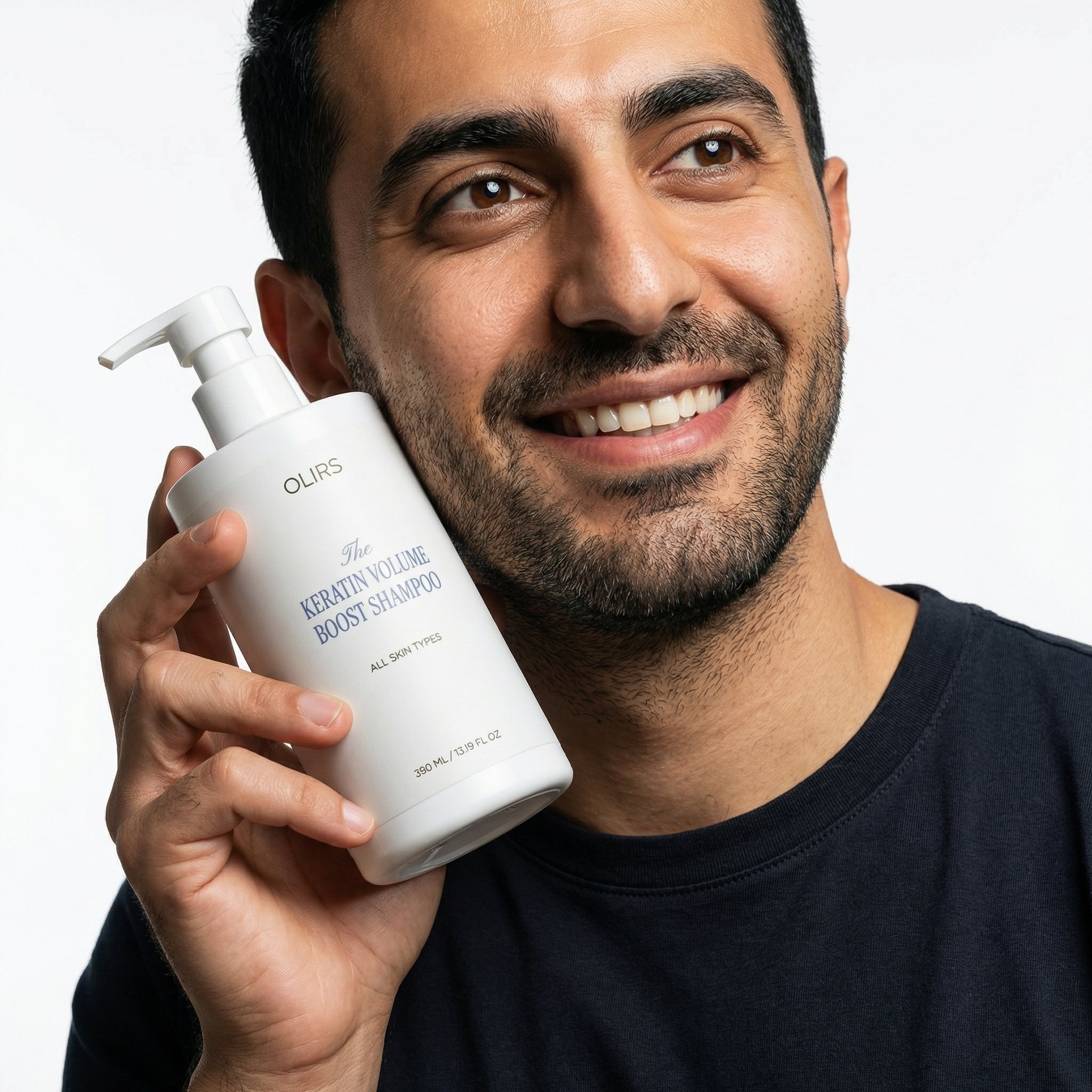 Man holding The Keratin Volume Boost Shampoo bottle with a smile, showcasing its benefits for fuller-looking hair.